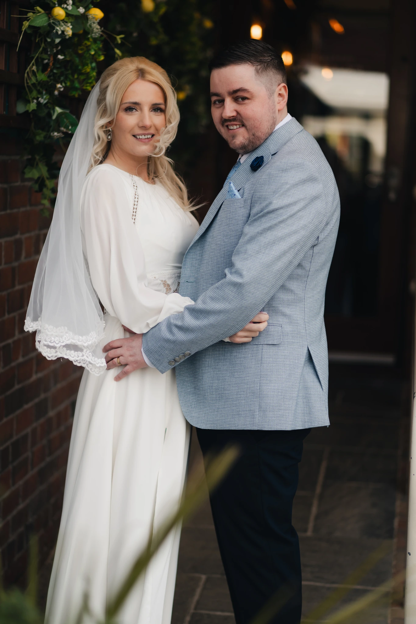 a bride and groom pose in front of their wedding venue