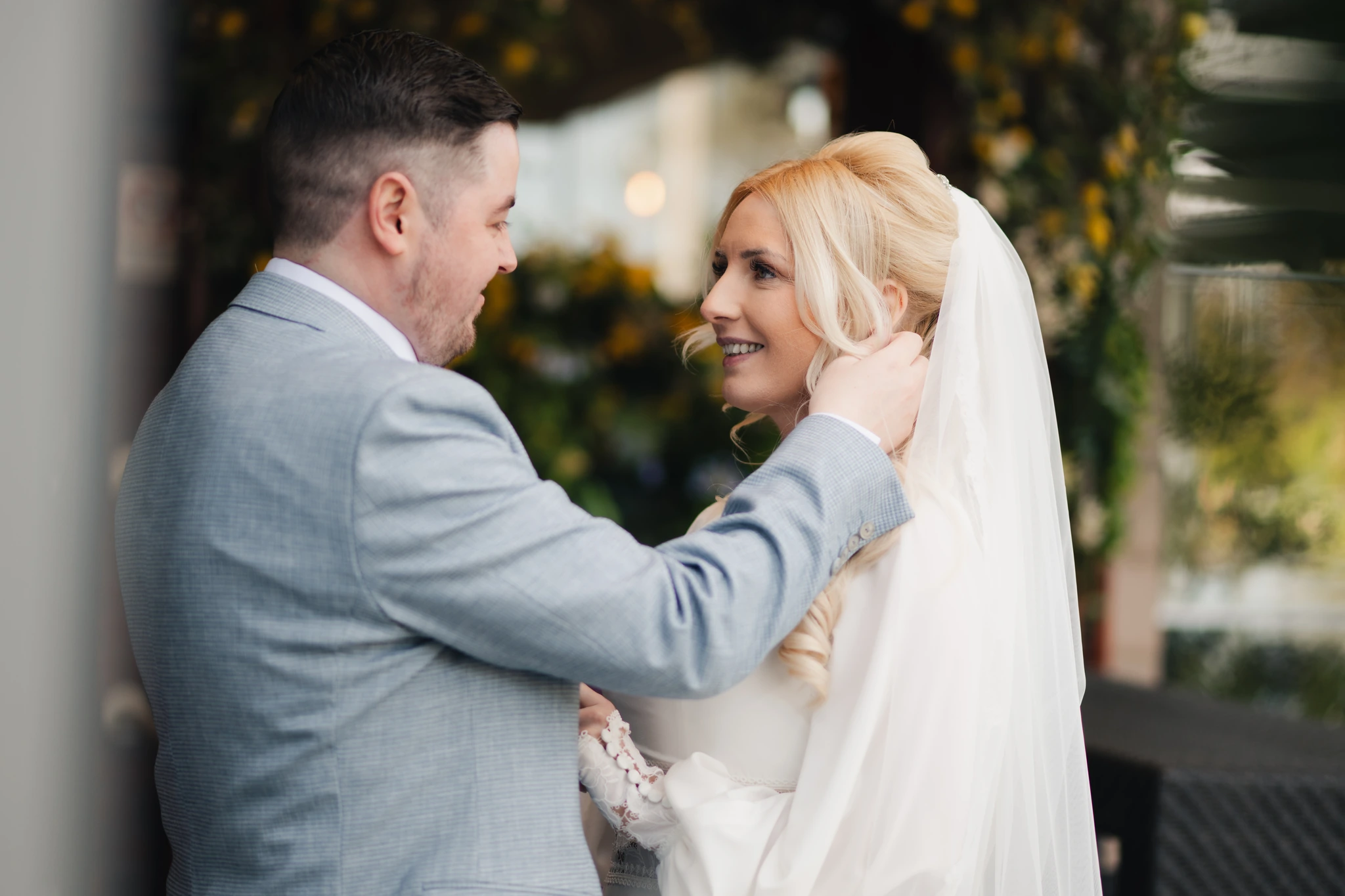 a bride and groom look at each other and smile as they kiss for the first time