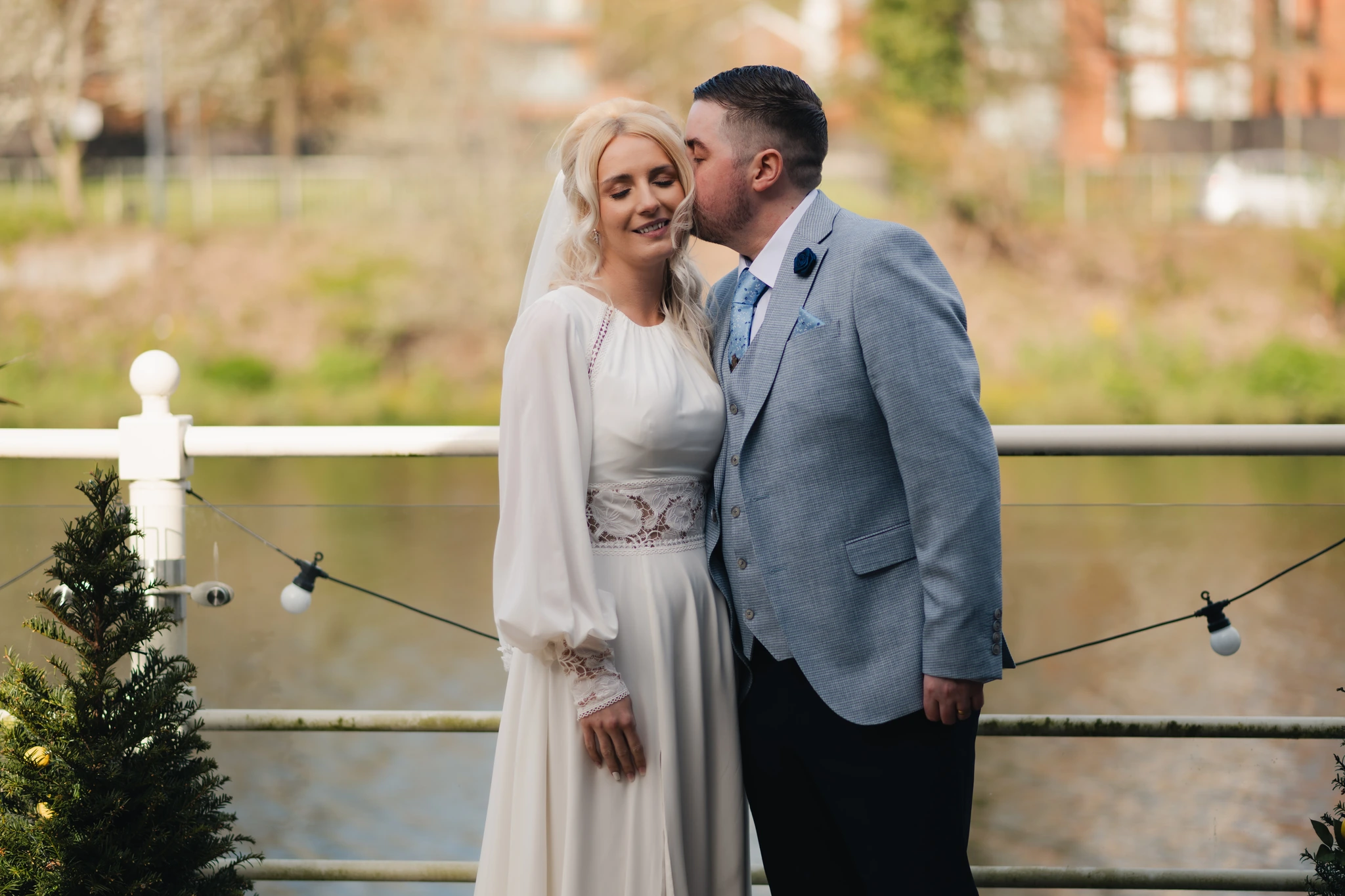 a bride and groom kissing in front of a river