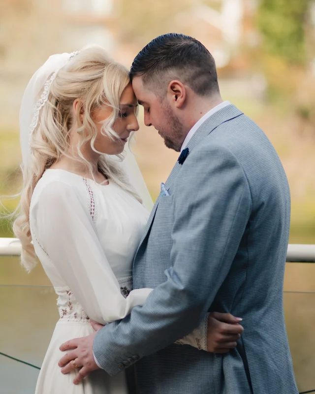a bride and groom embracing in front of a river