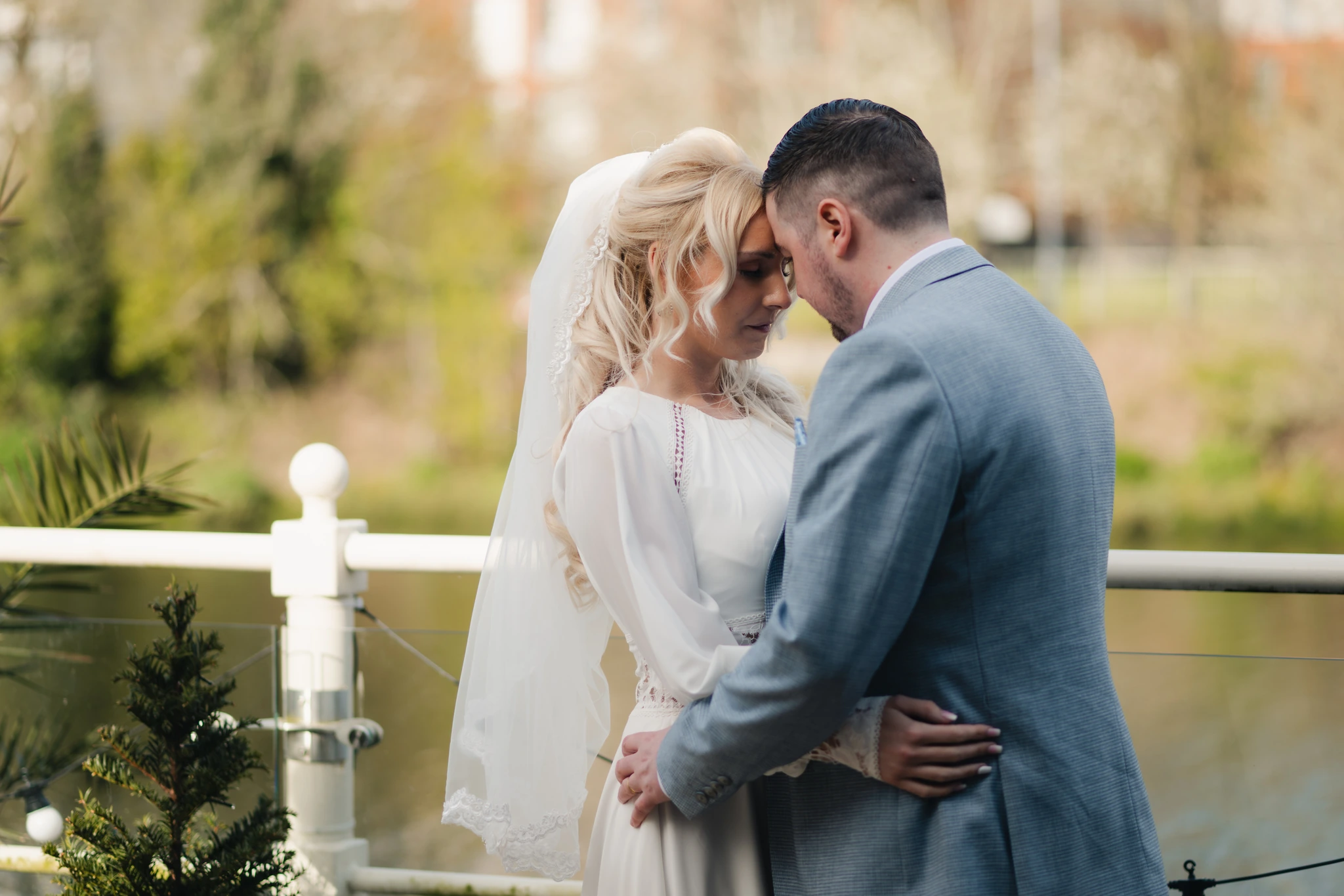 a bride and groom embracing in front of a river