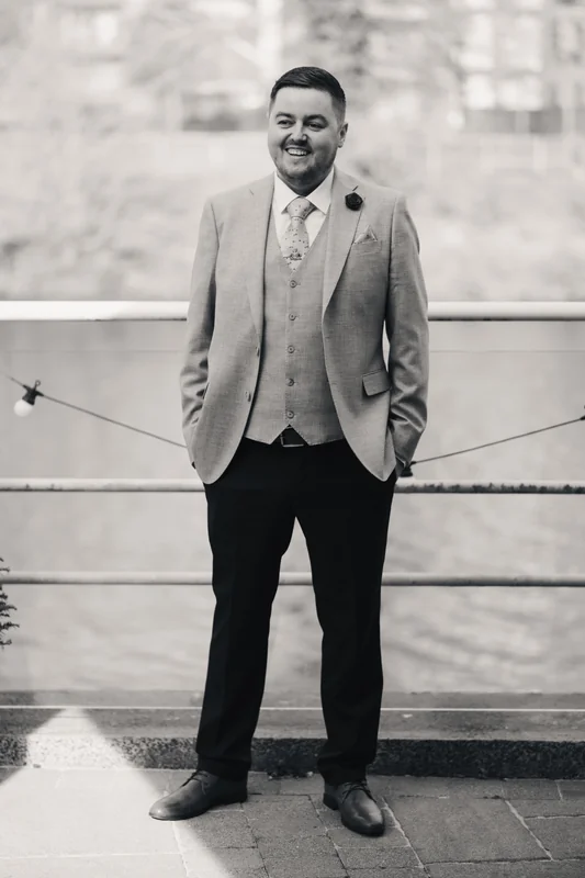 a man in a suit and tie standing next to a river
