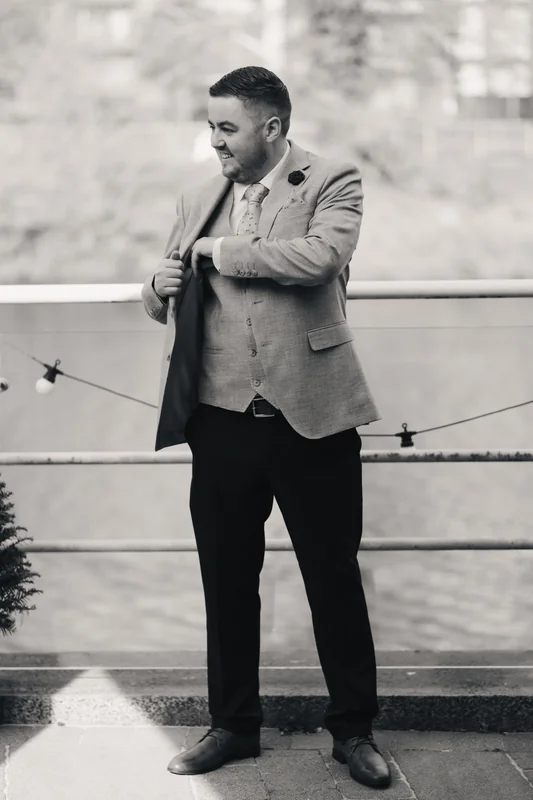 a man dressed in a suit and tie is standing on a balcony overlooking a river