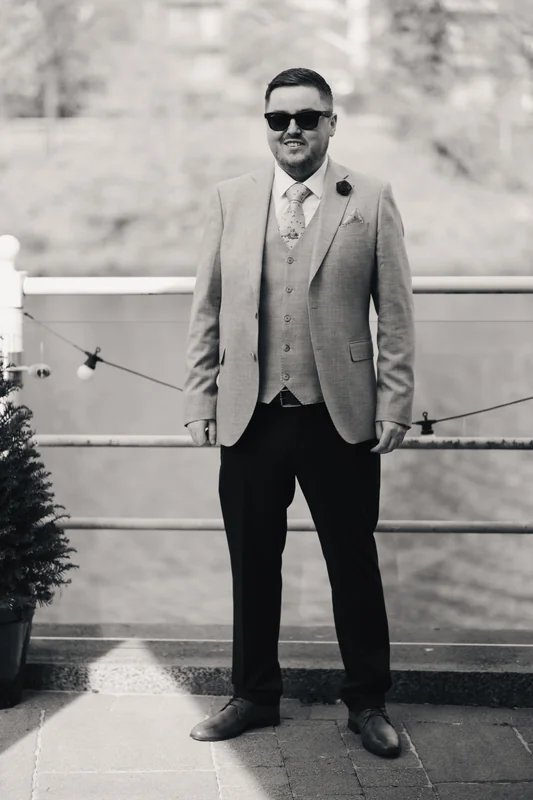 a man in a suit and tie standing next to a river