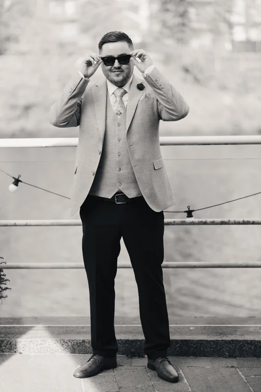 a man in a suit and tie standing next to a river