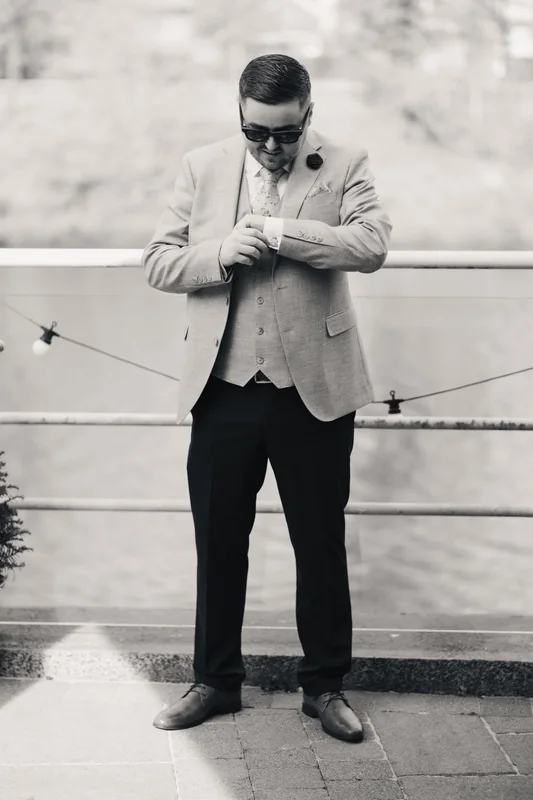 a man in a suit and tie standing next to a river
