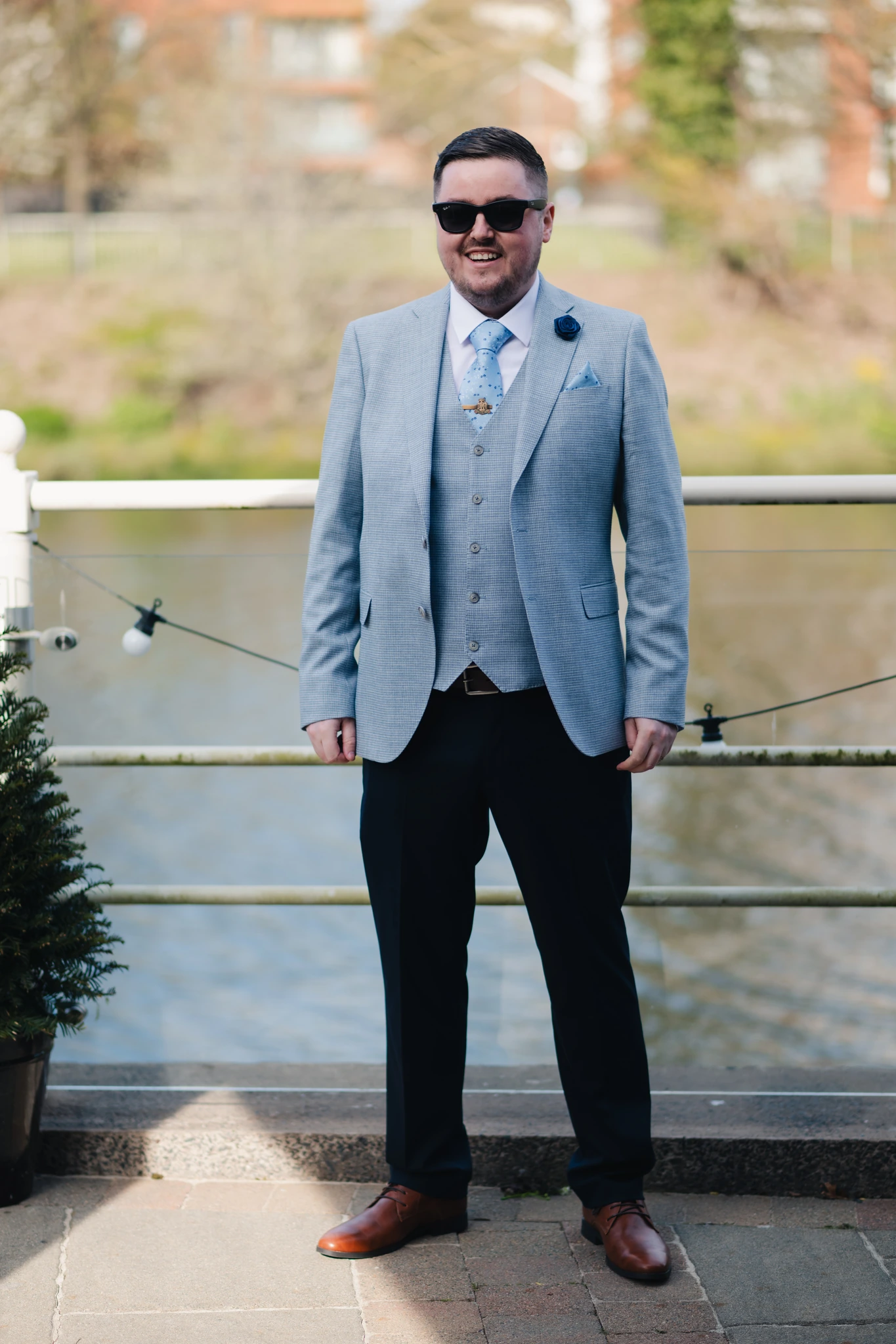 a man in a blue suit standing next to a river