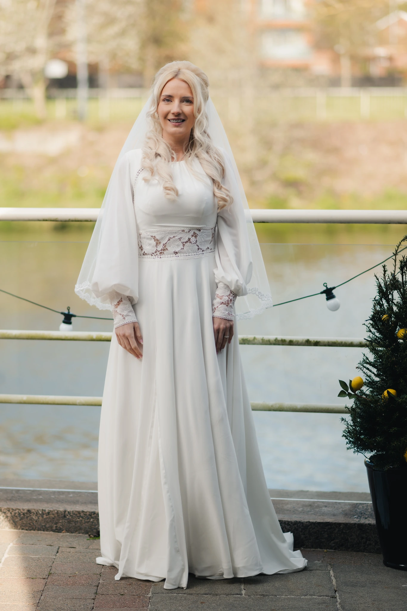 a woman in a white wedding dress standing next to a river