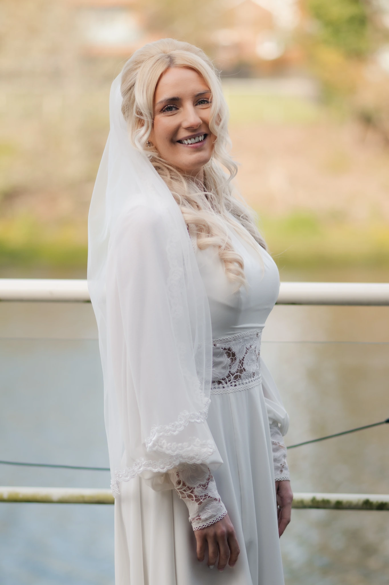 a bride in a white wedding dress standing on a balcony overlooking a river