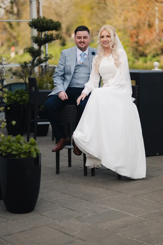 a bride and groom sitting on a bench in a garden