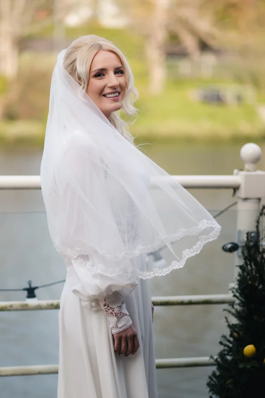 a bride in a white wedding dress and veil posing on a boat