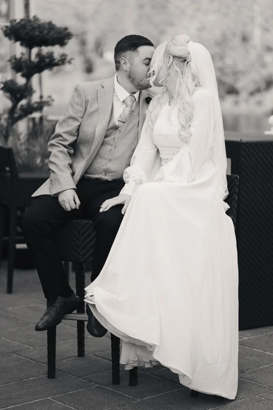a bride and groom kissing on a wooden bench