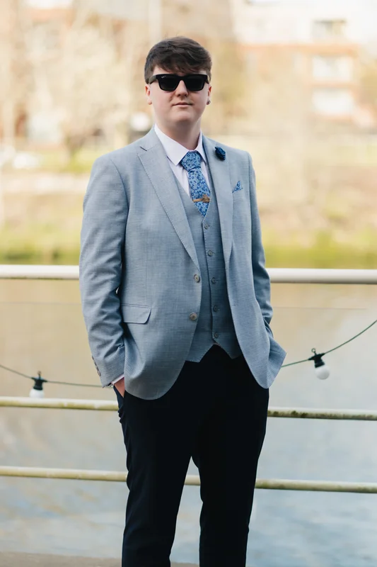 a man in a blue suit and tie standing next to a river