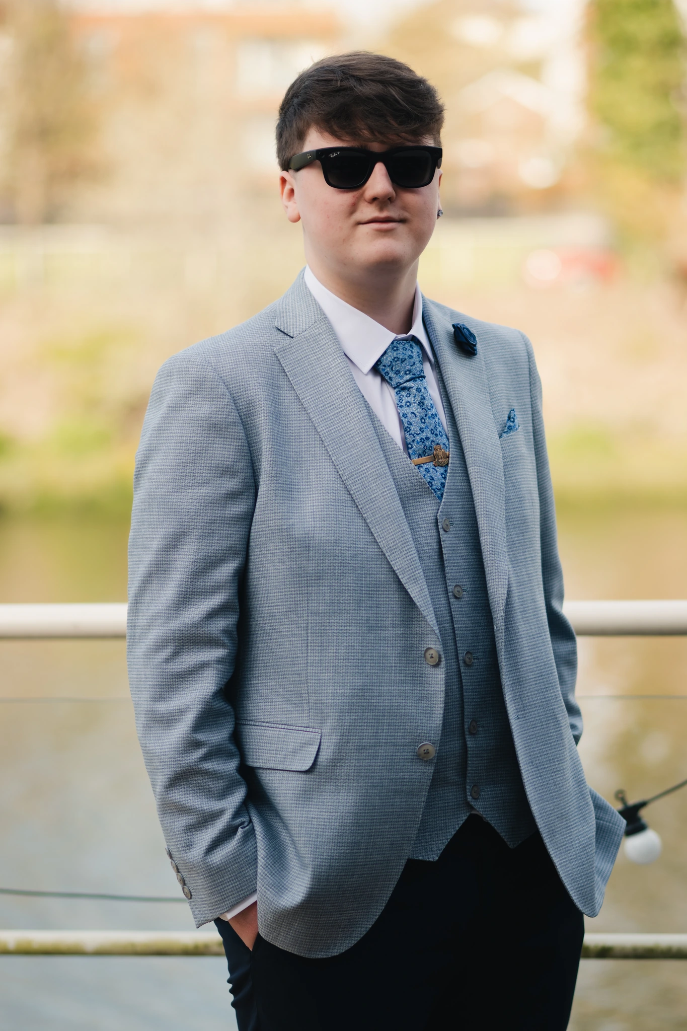 a man in a suit and tie standing next to a river