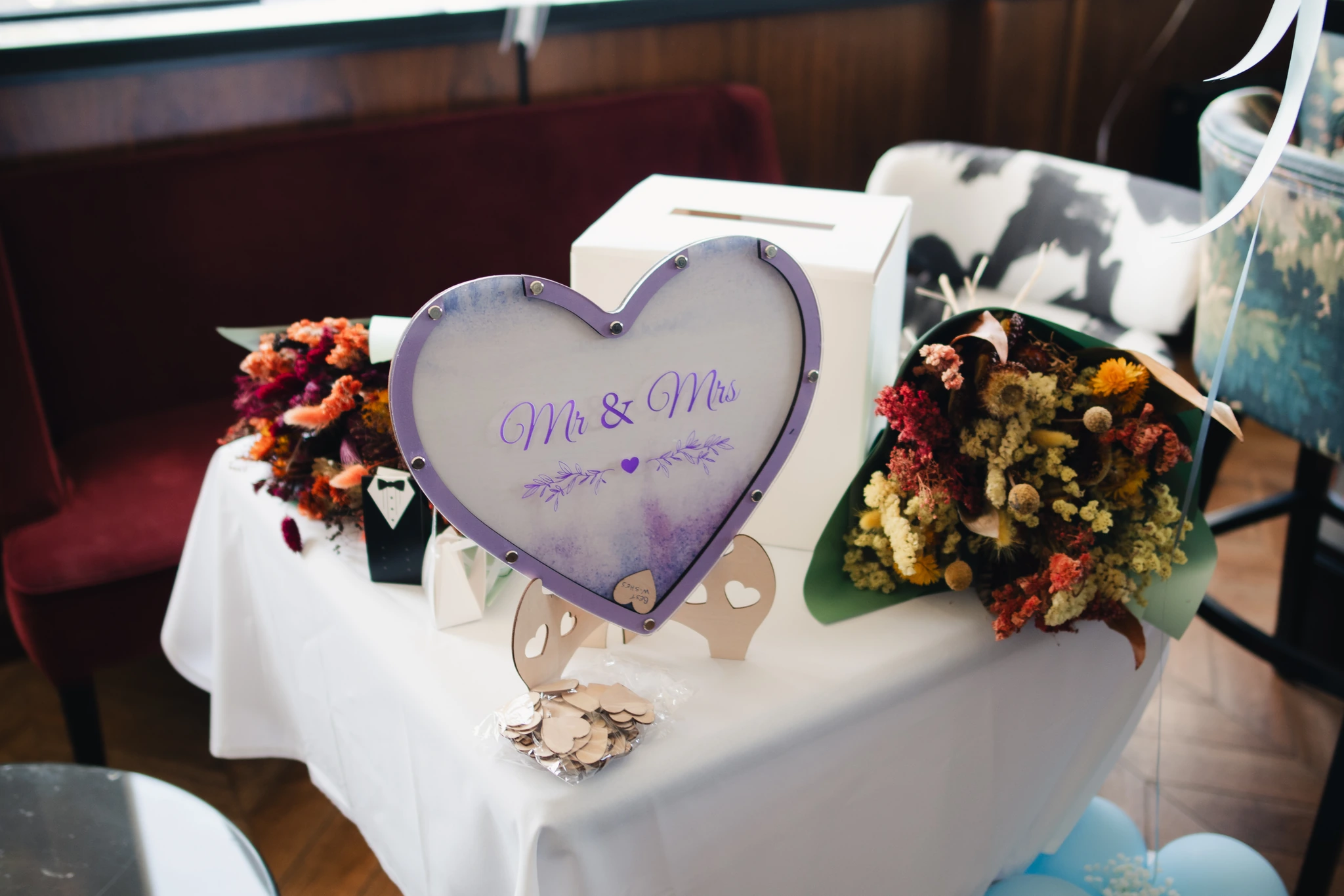 a table with a heart shaped cake stand and flowers on it