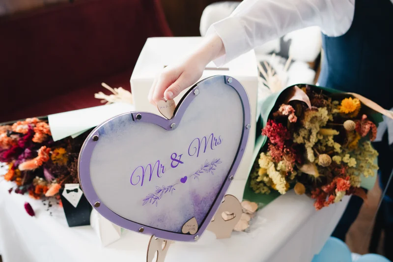 a man is holding a heart shaped frame with flowers on it