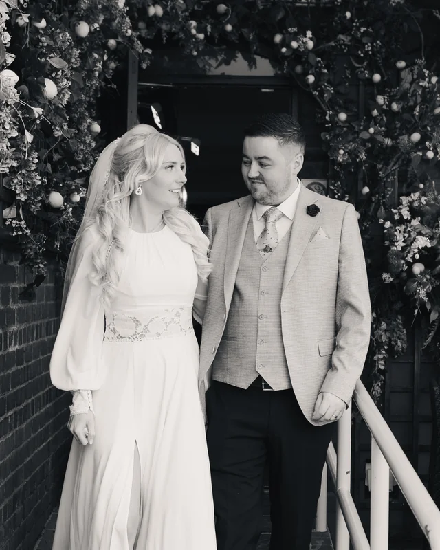 a bride and groom standing in front of a black and white photograph