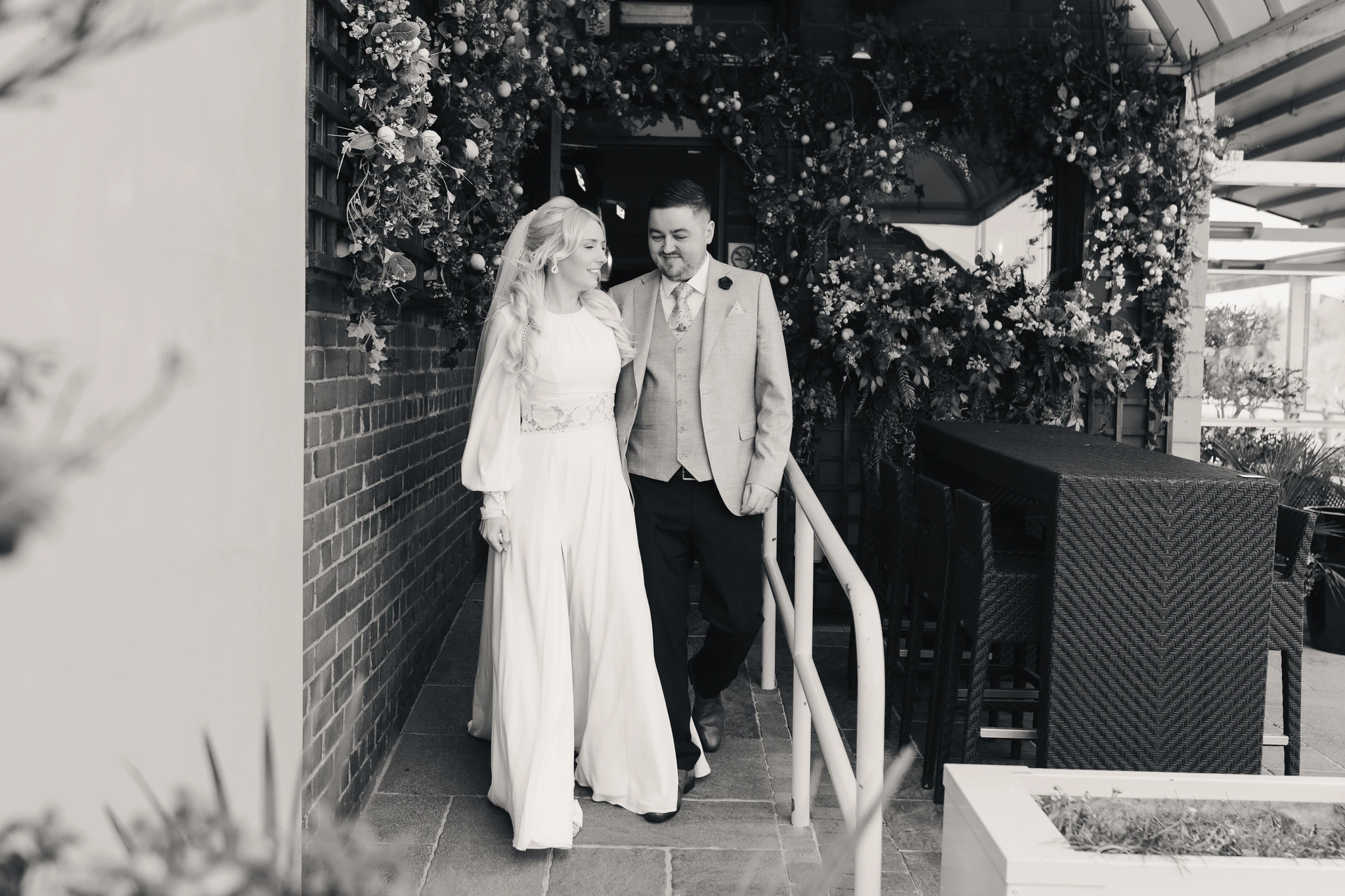 a bride and groom walk down the stairs of their wedding venue