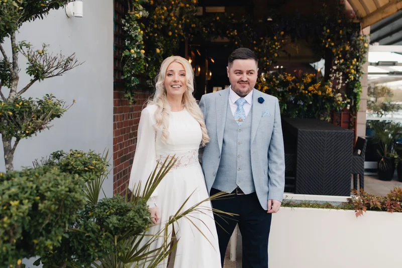 a bride and groom pose for a photo in front of their wedding venue
