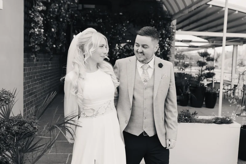 a bride and groom look at each other as they walk down the aisle