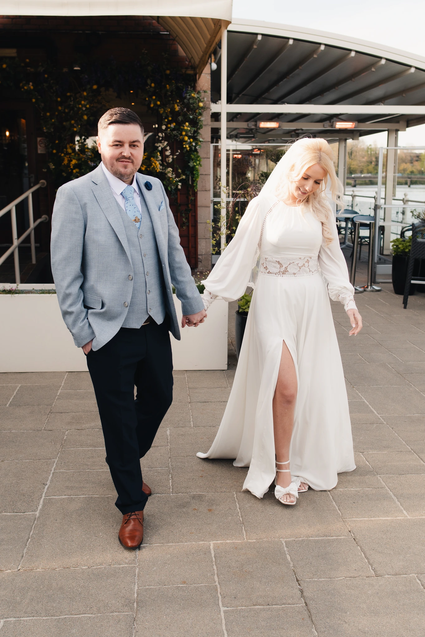 a bride and groom are walking down a stone walkway in front of a restaurant