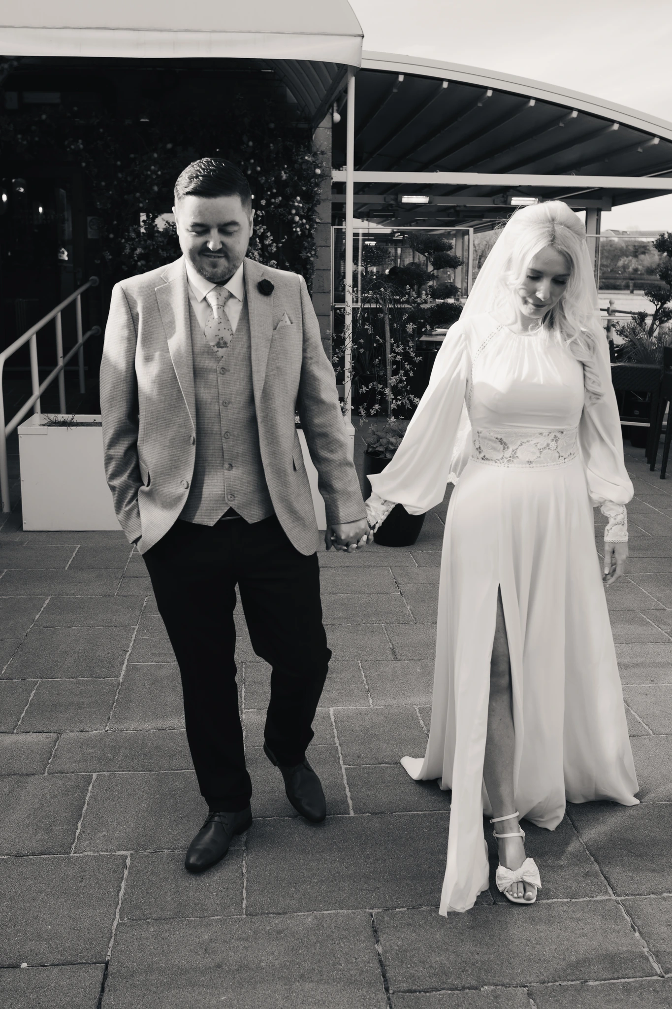 a bride and groom walk down a street in front of their wedding venue