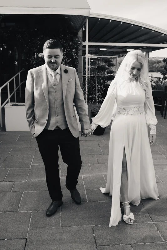 a bride and groom walk down a street in front of their wedding venue