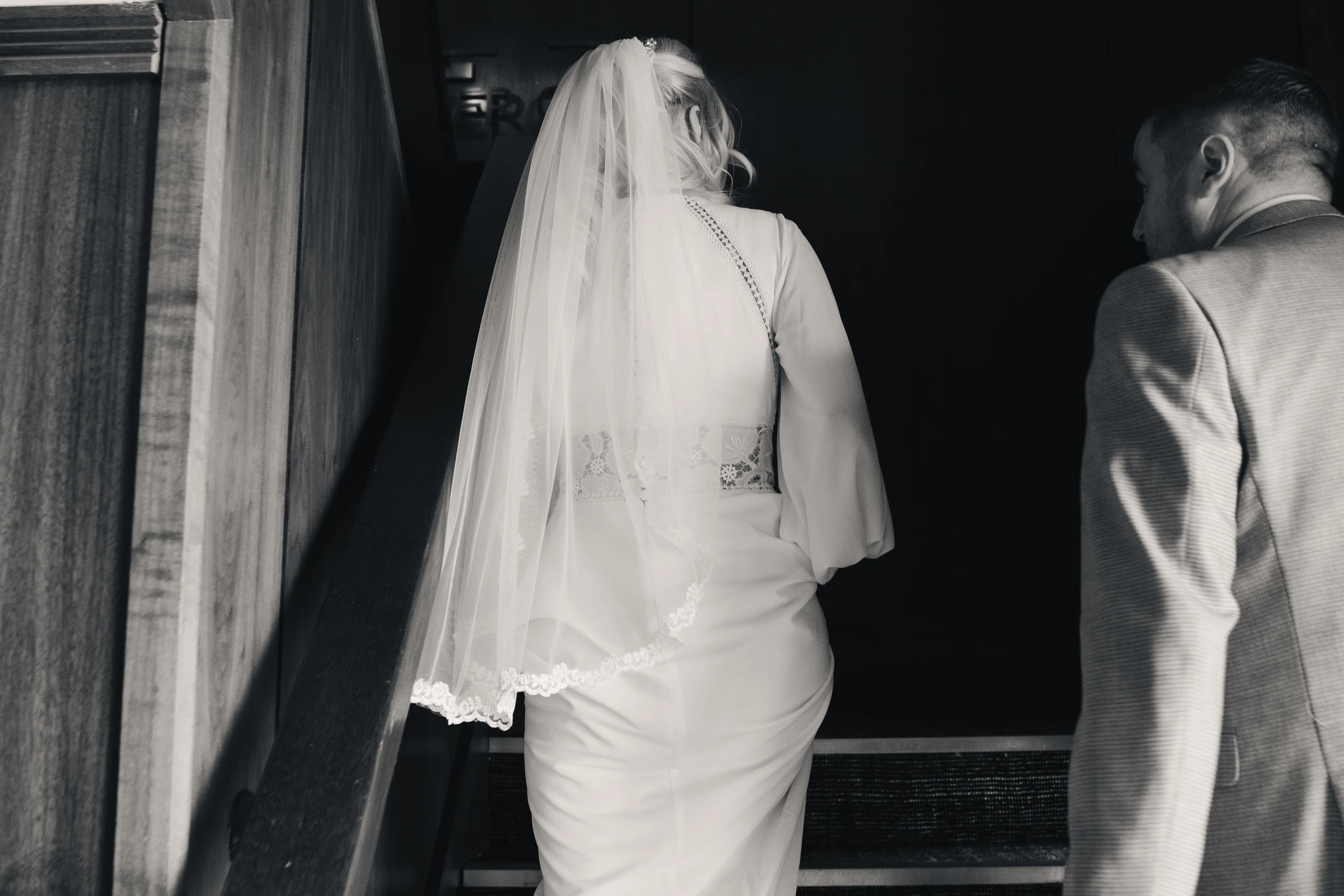 black and white image of bride and groom walking down stairs