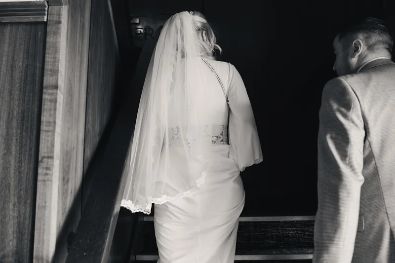 black and white image of bride and groom walking down stairs