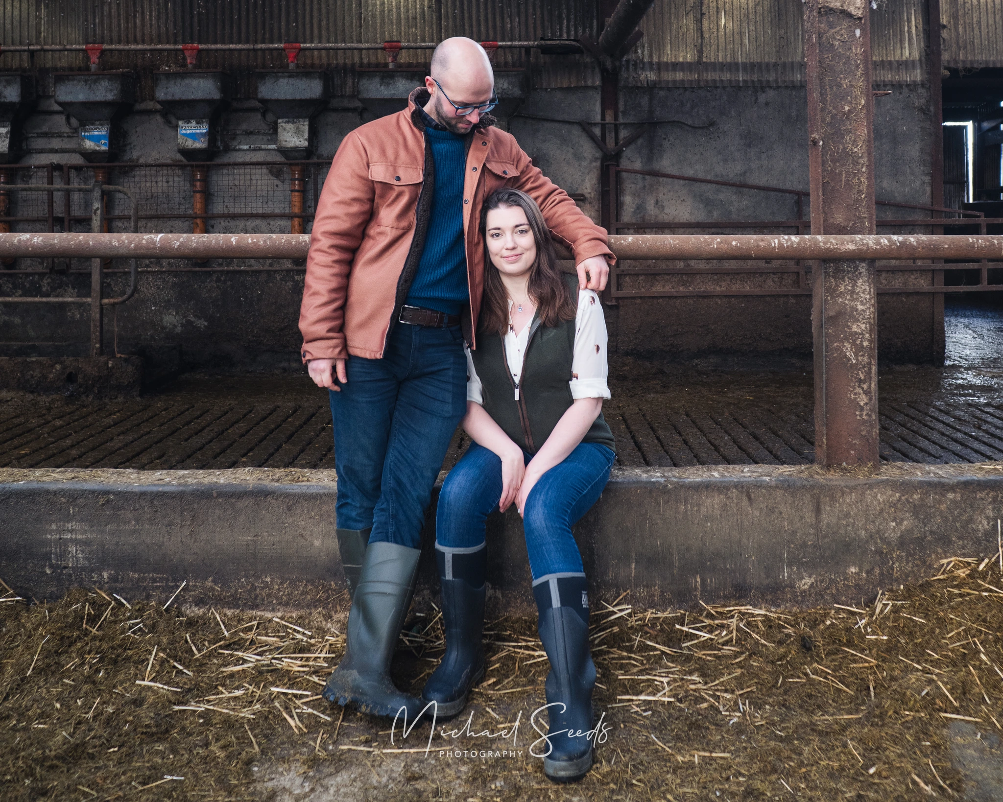 a couple sitting on the floor of a barn
