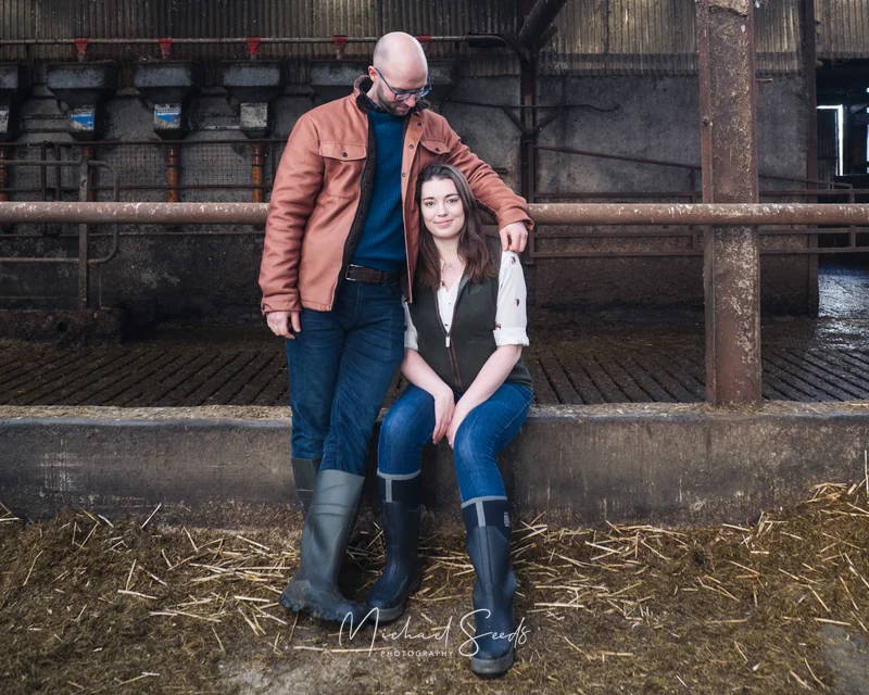 a couple sitting on the floor of a barn