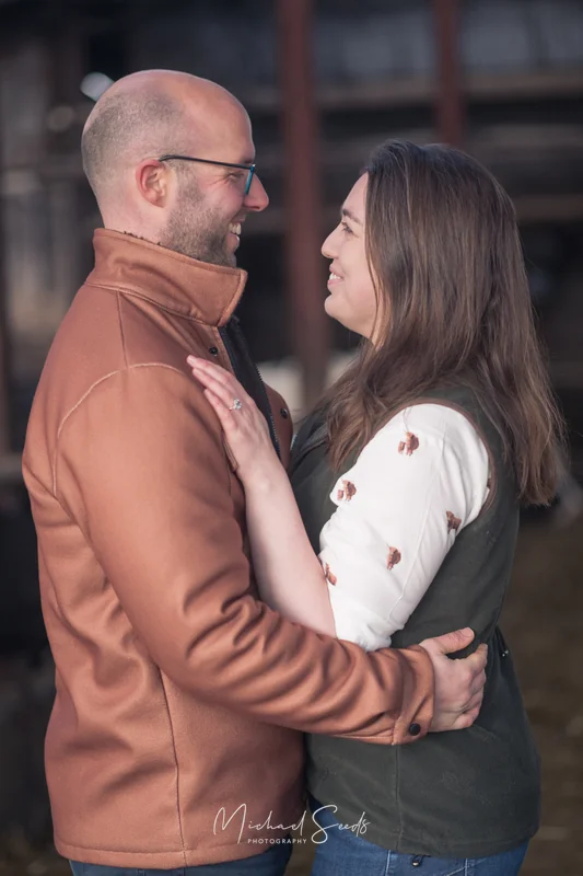 a couple hugging each other in front of a barn