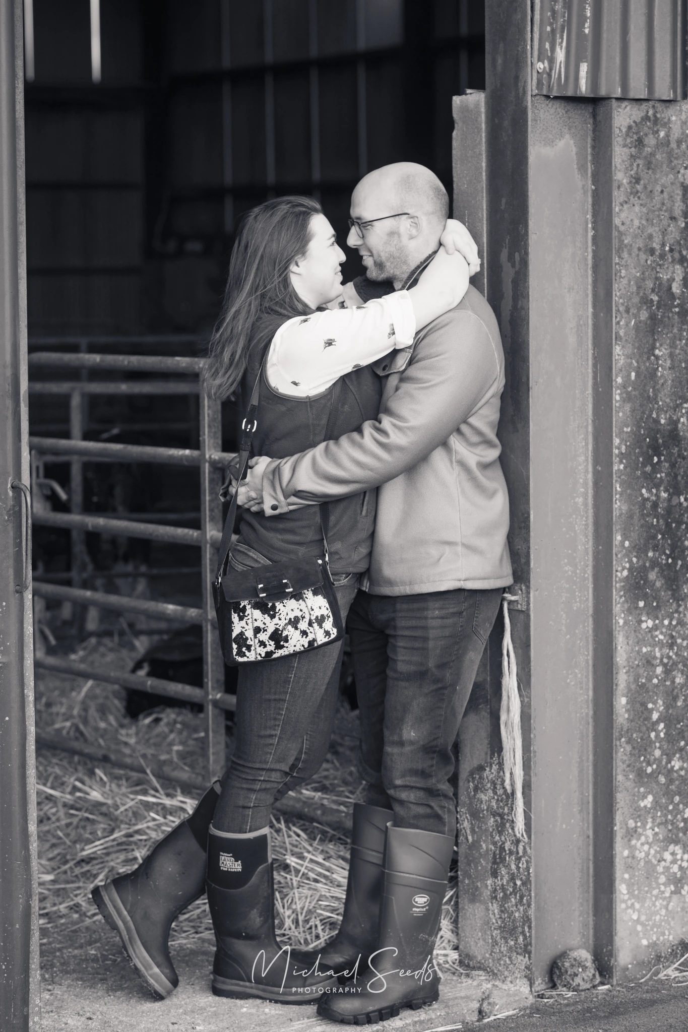 a man and woman hugging in front of a barn door