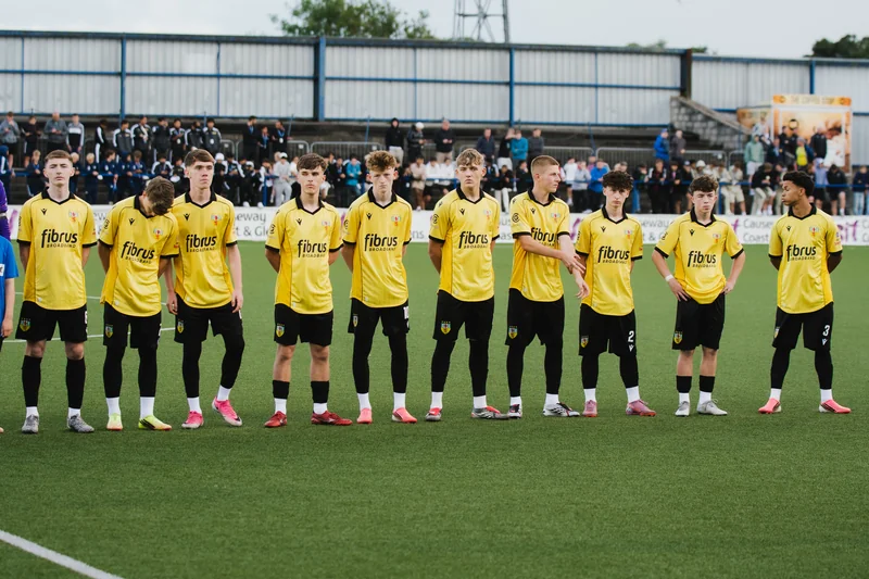 a group of boys in black and yellow shirts standing on a soccer field