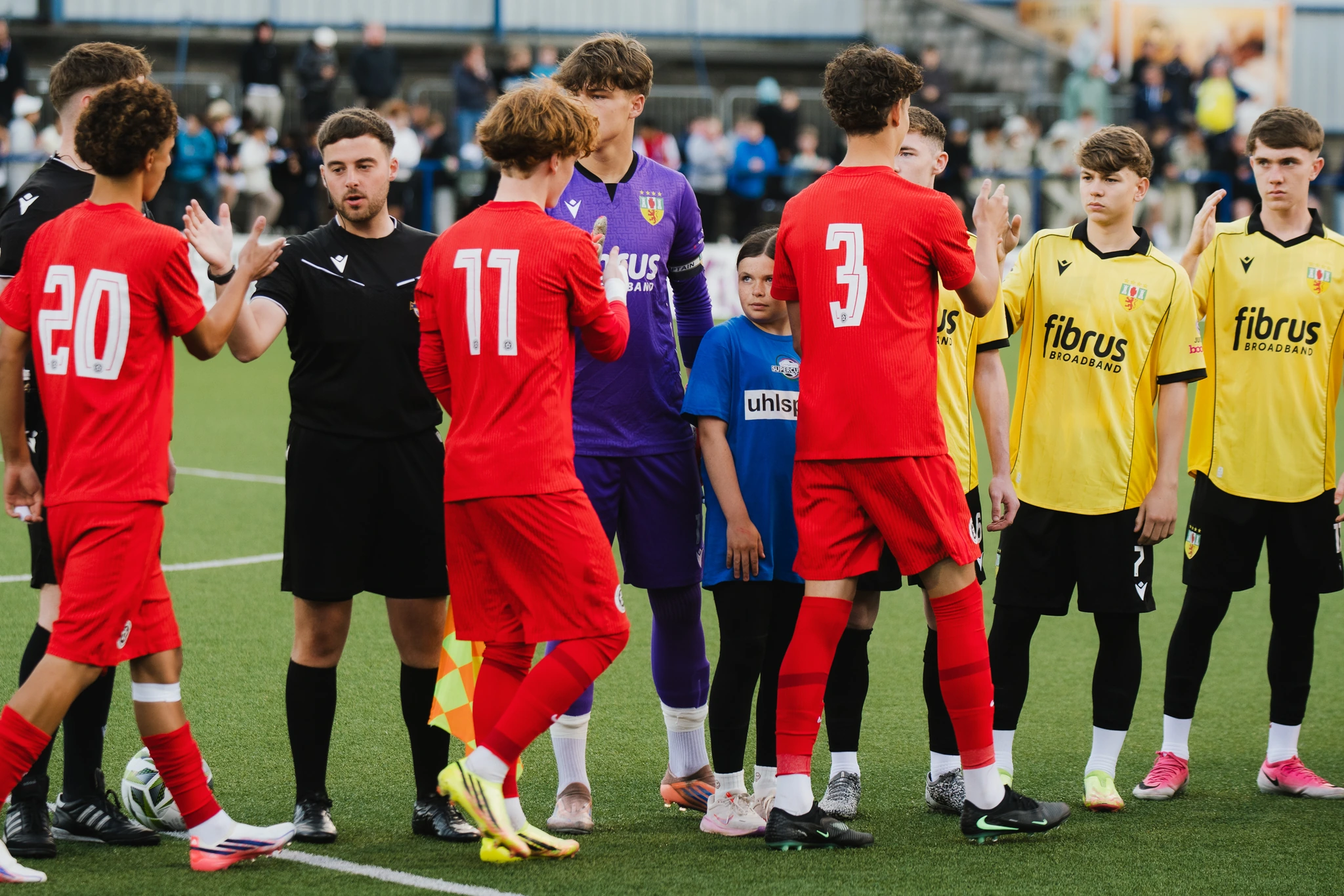 a group of soccer players standing on a field with a referee in the background