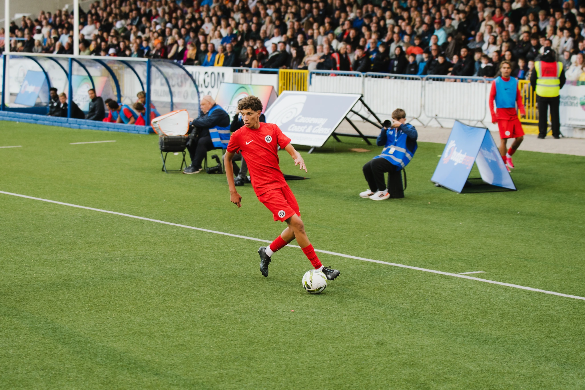 a soccer player kicks a ball in front of a crowd at a stadium