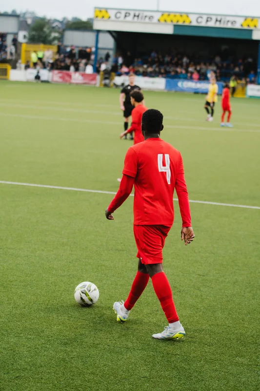 a man in a red soccer uniform kicking a ball in front of a crowd