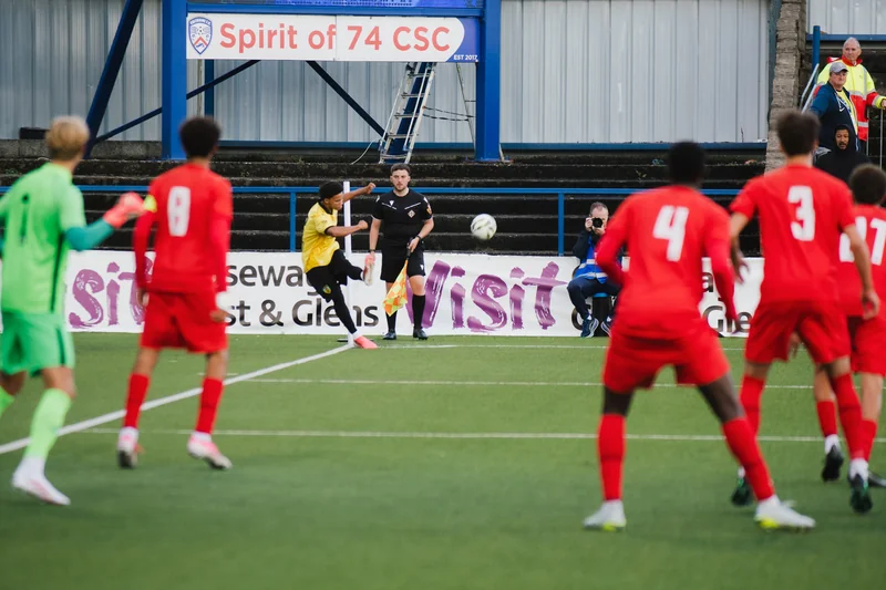 a group of boys playing soccer on a field in front of spectators