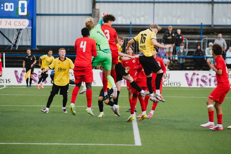 a group of soccer players jumping for a ball on a field