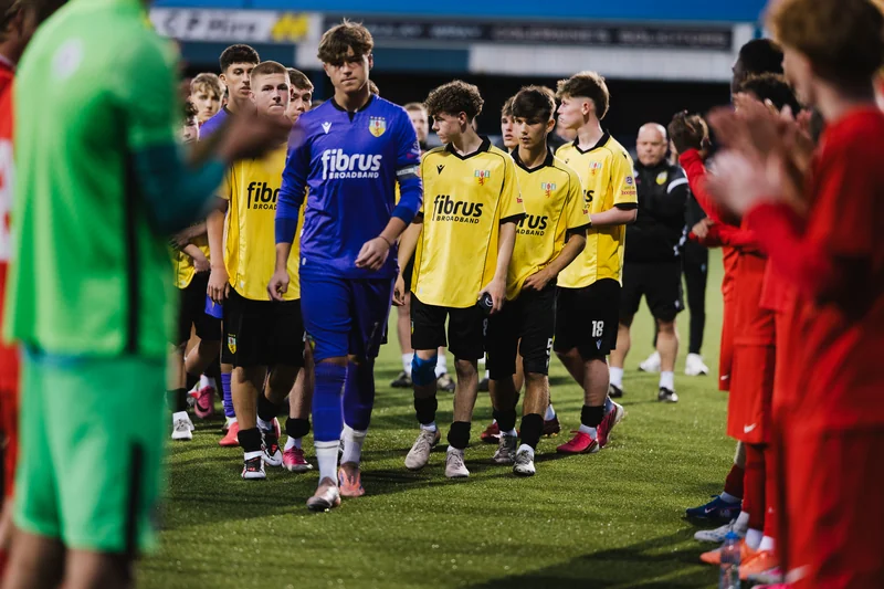 a group of soccer players standing on a pitch in front of a stadium