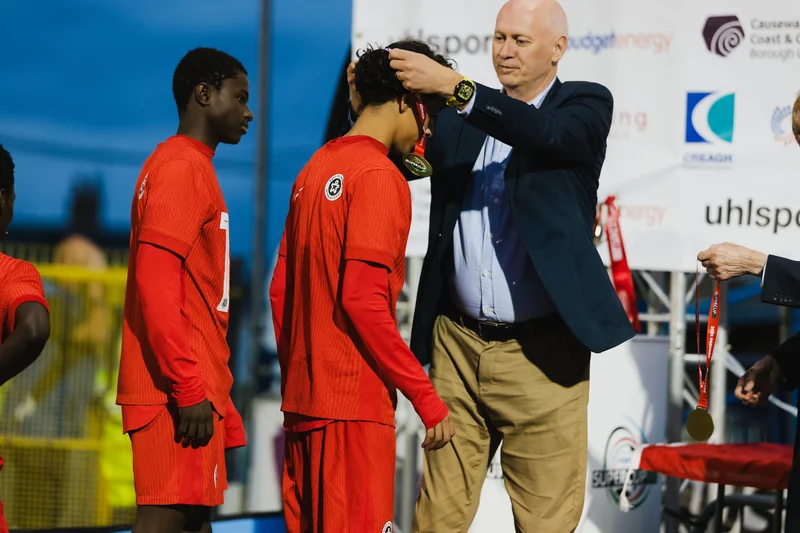 a man is putting a cap on a young boy in front of a crowd of spectators