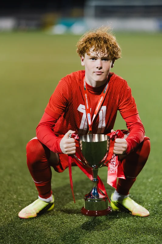 a young man with a trophy in his hands on a soccer field
