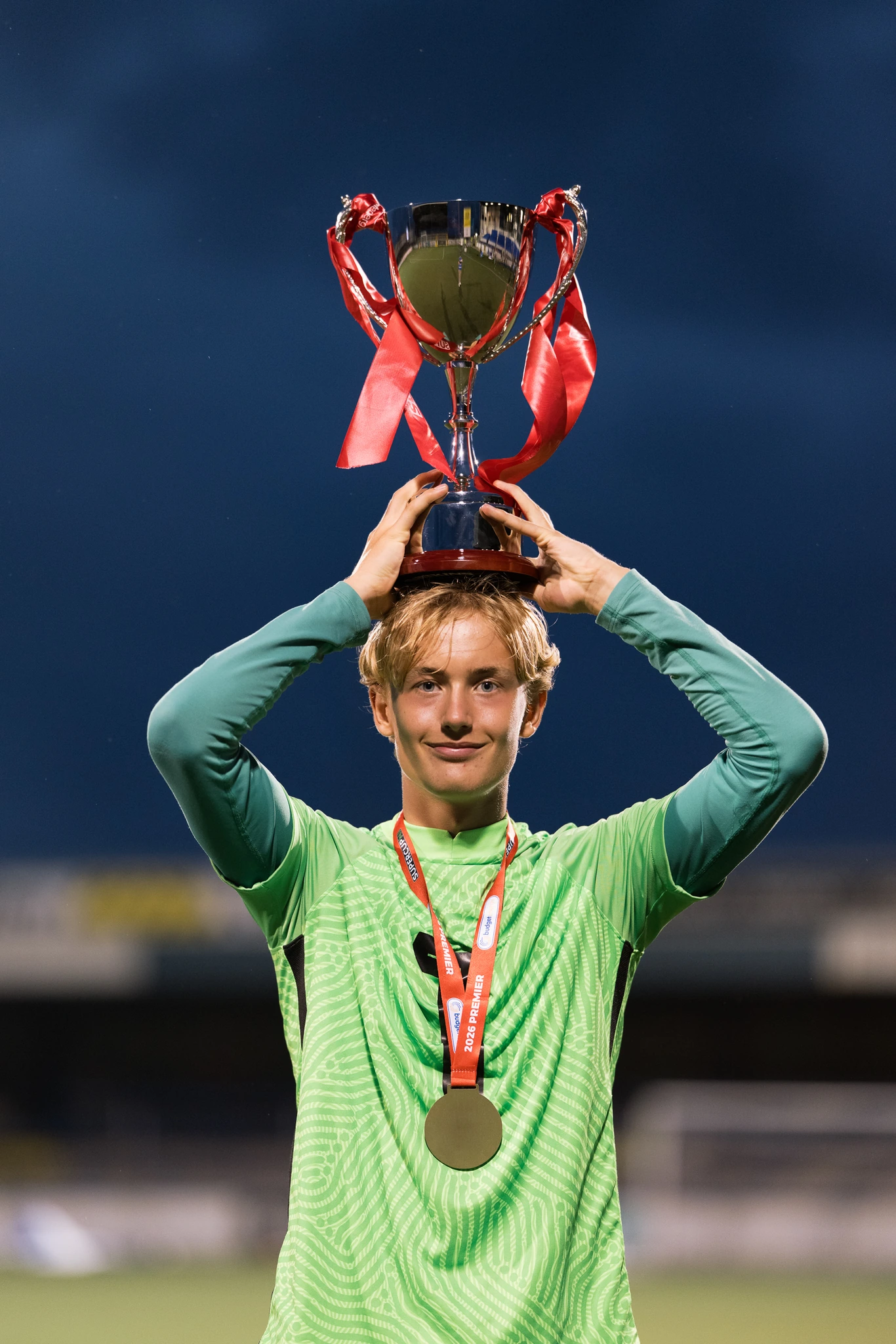 a young soccer player holds up a trophy on a soccer field