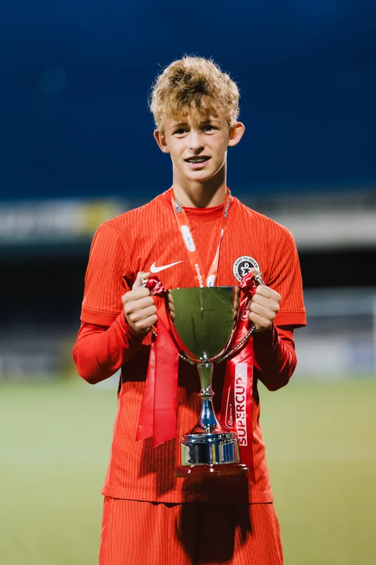 a young man with a trophy in his hands on a soccer field