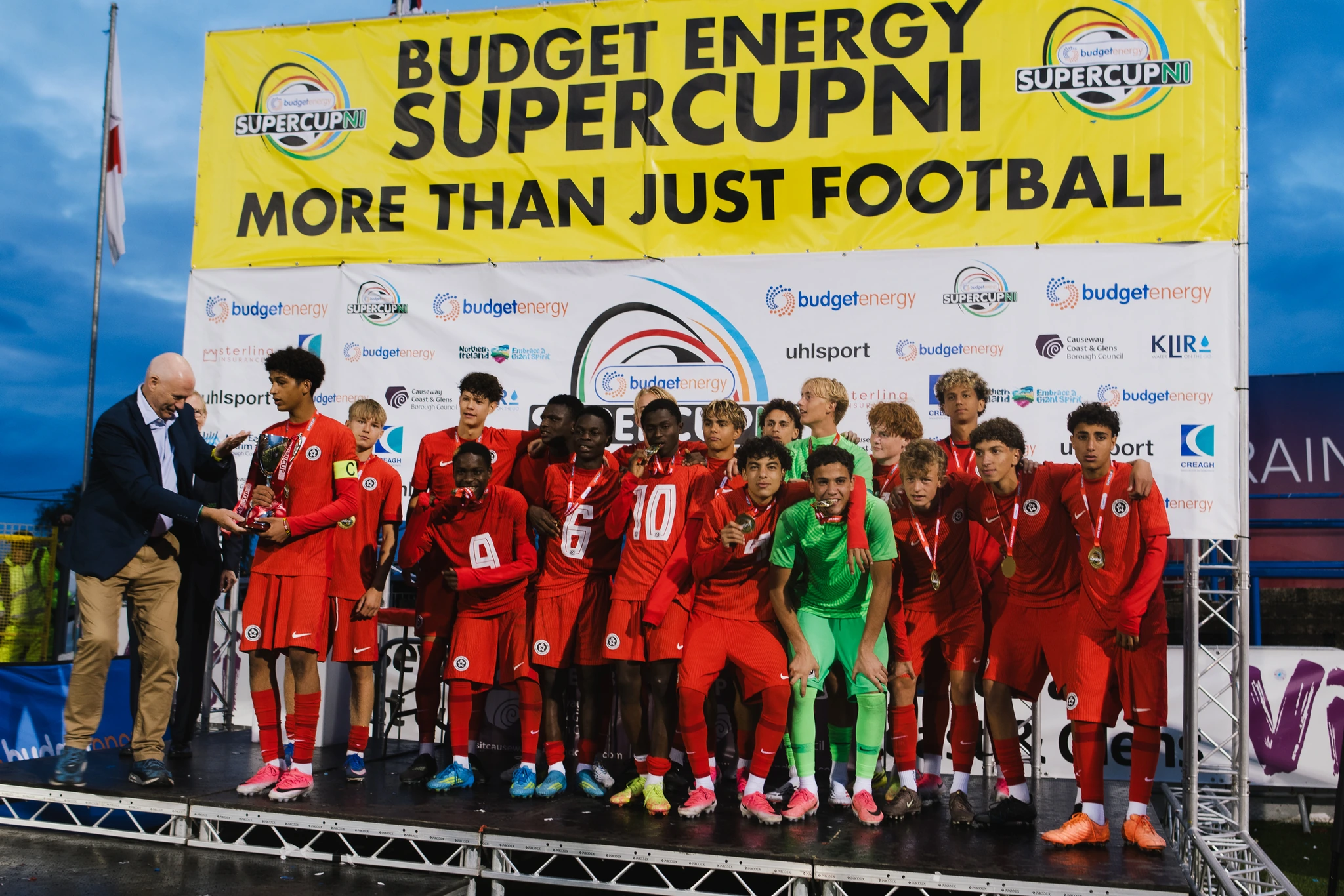 a group of soccer players standing on a stage with a banner that says budget energy super cup
