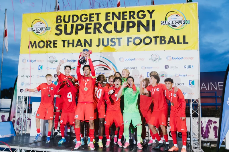 a group of soccer players standing on a stage with a trophy