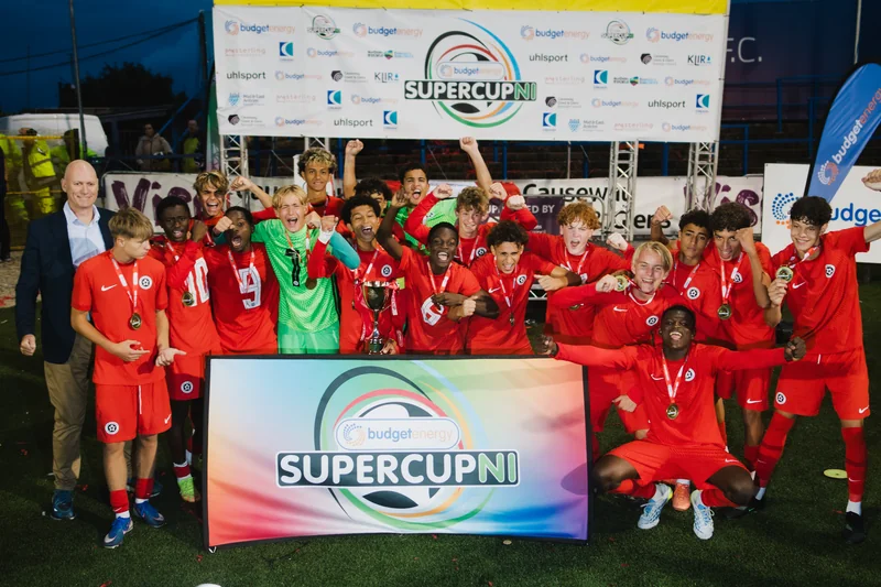 a group of soccer players standing on a field with a trophy