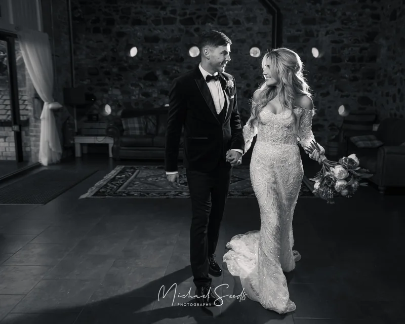 a bride and groom walk down a dark hallway