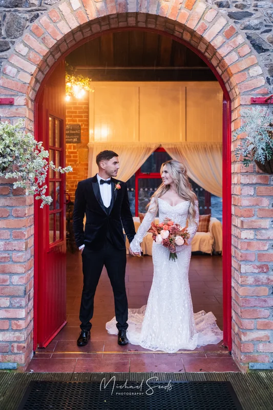 a bride and groom standing in front of a red doorway at their wedding reception