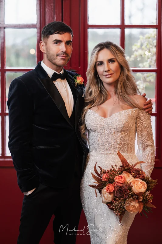 a bride and groom standing in front of a red door